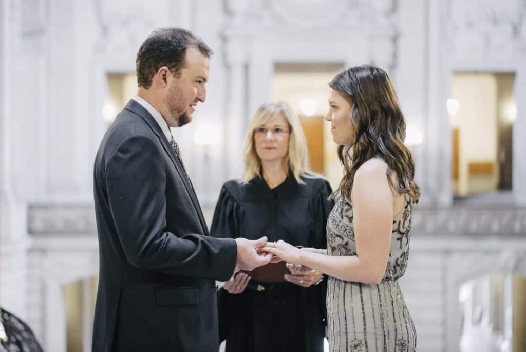 A man and woman exchange their wedding rings in a courtroom.