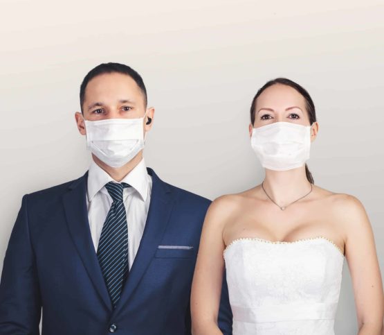 A bride and groom wearing surgical masks.